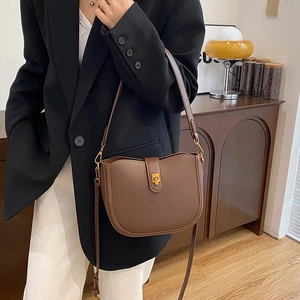 Vintage dark brown saddle bag with gold buckle on a stylish model in professional attire