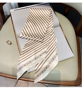 Détail d'un twilly en soie à rayures bicolores beige et motif monogramme pour sac à main