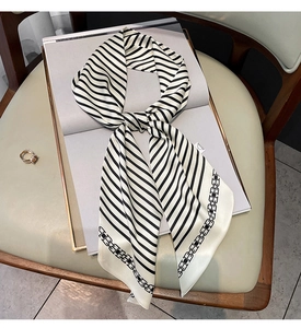 Détail du foulard en soie rayé noir et blanc avec motif chaîne sur un livre