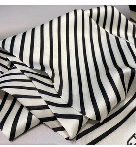 Gros plan d'un foulard rayé noir et blanc au fini satiné montrant les plis du tissu soyeux