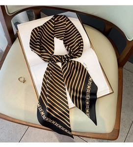 Détail d'un foulard en soie rayé avec motifs de chaînes posé sur un livre