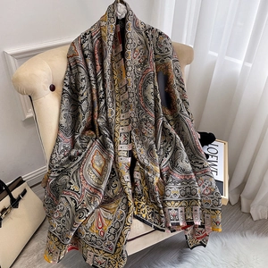 Élégant foulard en soie à motif paisley rouge et or vintage drapé sur un fauteuil chic