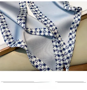 Detail of light blue silk scarf showing satin texture and geometric navy blue patterns