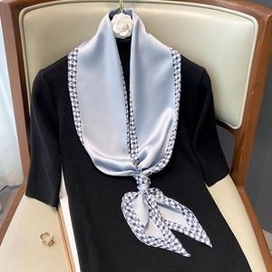 Elegant grey-blue silk scarf with navy checkerboard pattern tied on black shirt
