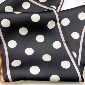 Detailed view of polka dot silk scarf featuring smooth satin texture and elegant pink edges