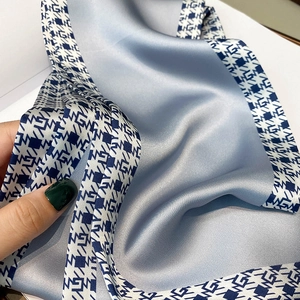 Detail view of smooth foggy blue satin scarf with elegant geometric patterns and soft texture