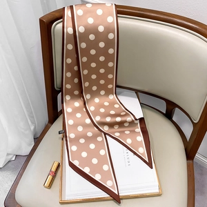 Polka dot skinny silk scarf in coffee and white displayed on a luxury leather chair