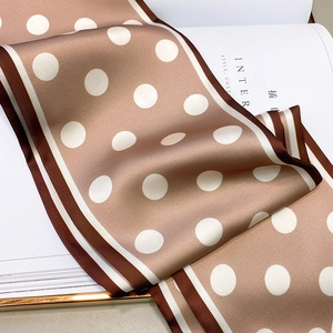 Close-up of champagne polka dot silk scarf with contrast striped edges on white paper