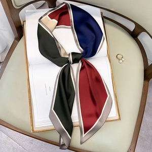 Narrow silk scarf with polka dots and color-block pattern tied in a stylish knot