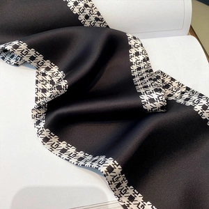 Close-up of silk texture scarf featuring a black satin center and houndstooth pattern border
