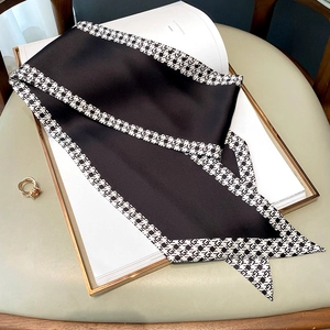 Close-up of black satin silk scarf with houndstooth edge and golden ring accessory