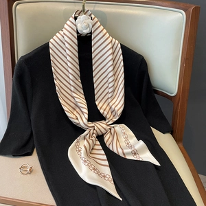 Foulard élégant en soie à rayures et motifs chaînes sur un pull en maille noir