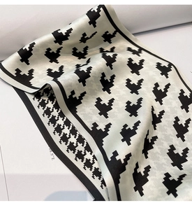 Detailed view of houndstooth silk scarf with black borders and smooth satin texture