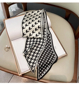 Detailed close-up of a houndstooth silk scarf with fine stitching and gold pearl ring detail