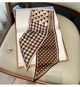 Detail of coffee houndstooth silk scarf on book with a pearl ring accessory