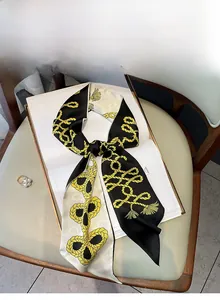 Détail d'un foulard étroit en satin style français avec motif corde jaune sur un livre