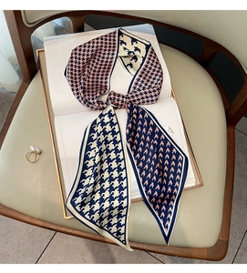 Detail of houndstooth silk-like scarf tied on a book, showing texture and elegant drape