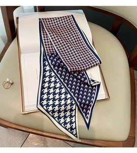 Detail of elegant houndstooth twilly scarf in navy and coral on a luxury book display