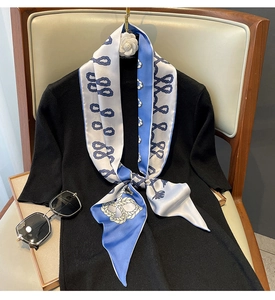 Détail d'un foulard en soie nautique bleu et blanc noué élégamment sur un pull noir