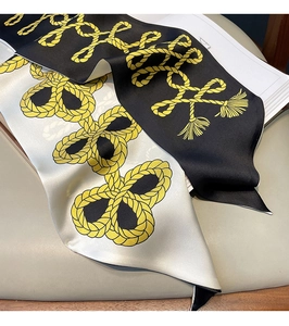 Gros plan d'un foulard en soie à motif corde jaune sur magazine blanc et cuir beige
