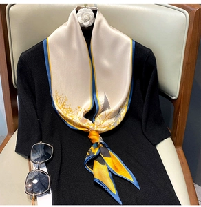 Detail of silk scarf tied on black top featuring golden tree patterns and blue borders