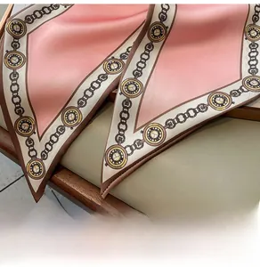 Detailansicht eines rosa Seidenschals mit Vintage-Ketten- und Uhrenmustern