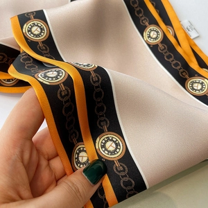 Detail eines schmalen Seidenschals mit Vintage-Goldketten und Taschenuhren-Drucken