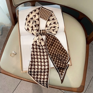 Brown and beige houndstooth silk scarf tied on a magazine with a soft leather background