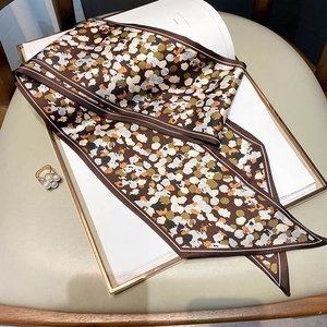 Detailed view of leopard print silk twilly scarf on book with elegant accessories