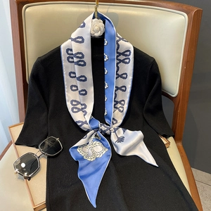 Foulard en soie bleu et blanc à motifs floraux porté sur un pull en maille noire