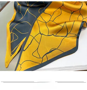 Dettaglio della sciarpa in seta a doppia faccia con motivo geometrico giallo e grigio
