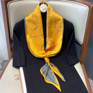 Elegante sciarpa in seta giallo zenzero con motivi geometrici grigi su maglia nera