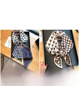 Détail de deux longs foulards en soie avec motif pied-de-poule bleu et marron sur plateau