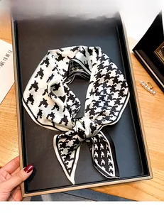 Vue détaillée d'une écharpe soyeuse à motif pied-de-poule dans un plateau noir chic