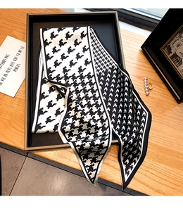 Détail d'un foulard étroit en soie à motif pied-de-poule noir et blanc élégant