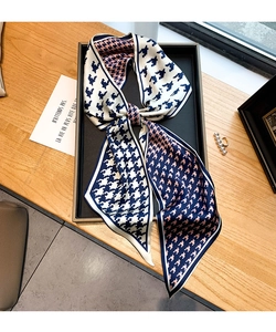 Détail du foulard en soie à motif pied-de-poule tricolore noué en nœud élégant