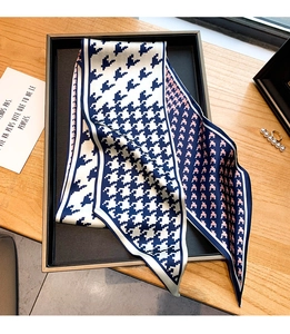 Détail d'un twilly en soie à motif pied-de-poule bleu, blanc et rose sur fond de bois