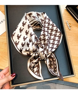 Détail d'un foulard en soie marron à motif pied-de-poule noué en nœud élégant