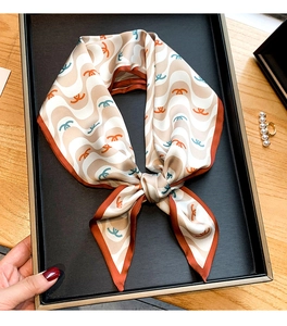 Détail d'un foulard en soie avec motifs géométriques en beige, caramel et bleu sarcelle