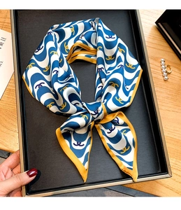 Gros plan d'un foulard étroit en soie avec motif ondulé et bordure orange sur plateau