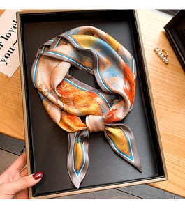 Foulard en soie à imprimé abstrait noué comme un cadeau sur une table en bois