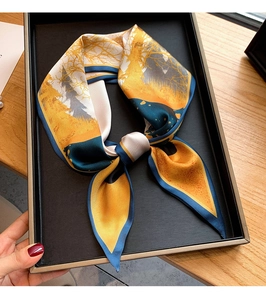 Détail d'un foulard en soie avec imprimé forêt jaune et bord roulé bleu en nœud