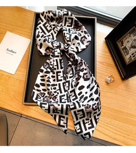 Détail d'un foulard en soie imprimé léopard avec lettres F dans un décor élégant