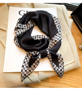 Détail d'un foulard en satin de soie noir noué avec imprimé géométrique sur les bords