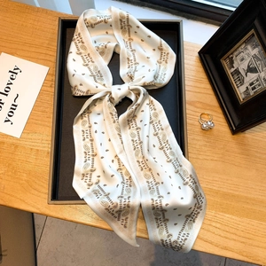 Élégante écharpe en imitation soie ivoire avec motif paisley nouée sur table en bois