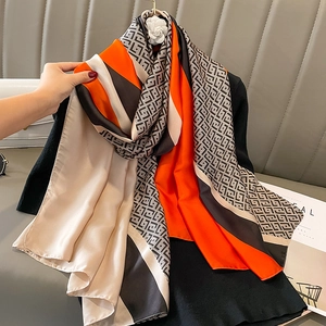 Women's silk-like scarf with orange and beige geometric patterns and camellia clip