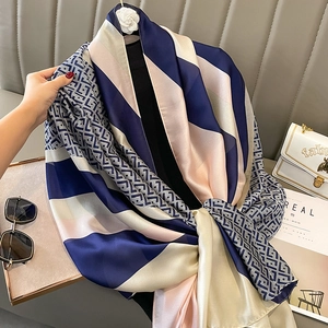 Elegant navy blue geometric silk scarf with pink stripes draped in a chic urban setting