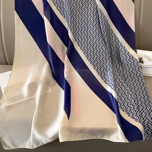 Detail of silk-like scarf with geometric patterns, navy and pink stripes, and elegant sheen