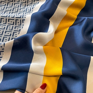 Macro view of navy and gold silk scarf with luxury geometric patterns and satin finish
