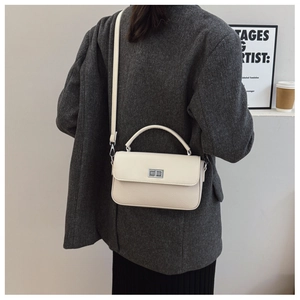 Close-up of cream square bag with lychee texture and silver twist lock on a wool coat